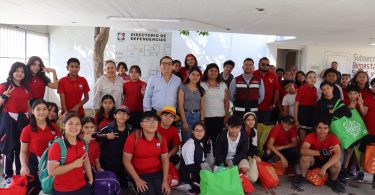 Alumnas y alumnos de la Primaria Benito Juárez posan con sus costales llenos de botellas recicladas junto a personal de la Subsecretaría de Bienestar, momentos antes de depositar el material en el contenedor para botellas PET.
